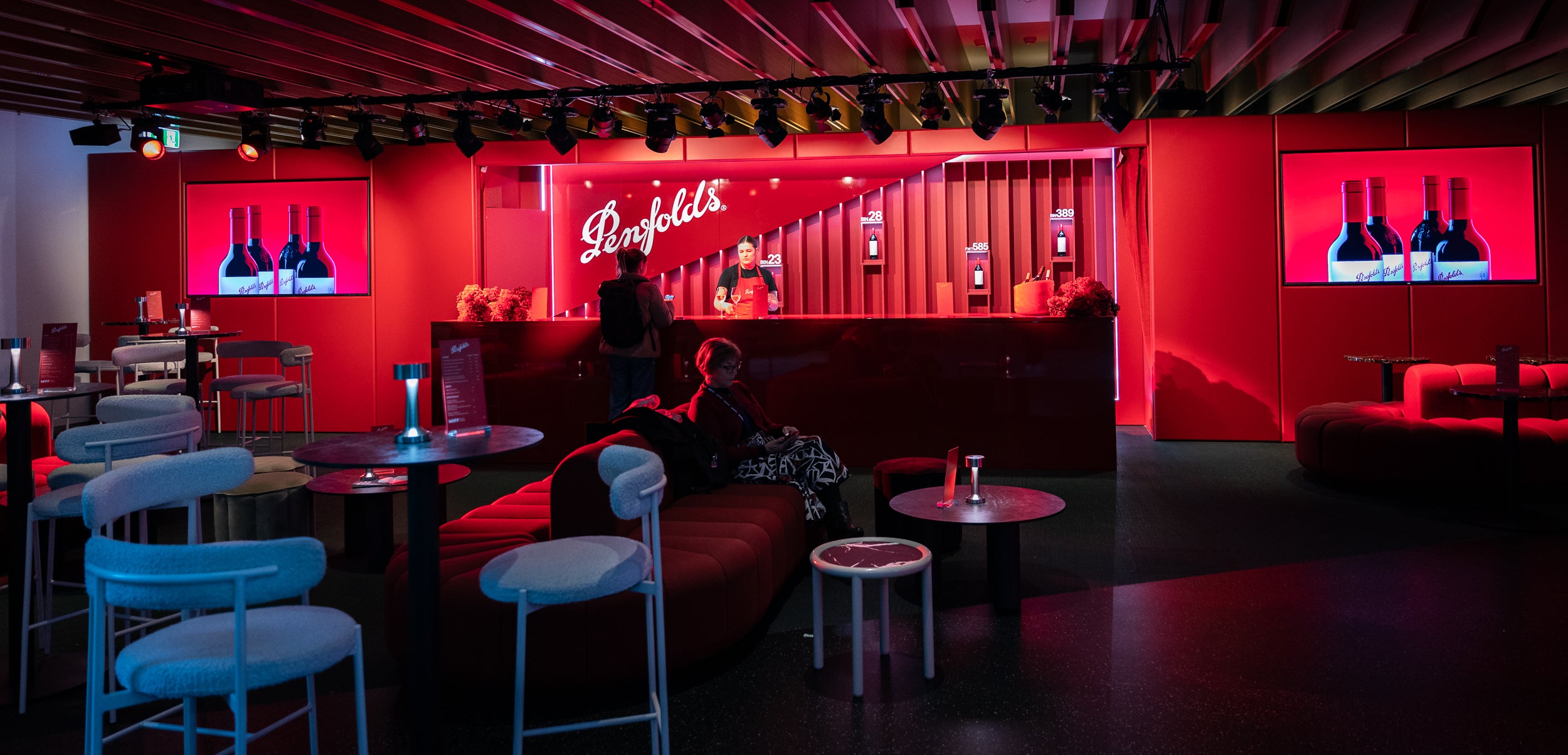 Bar interior with red lighting, 'Penfolds' branding, and bottles displayed.