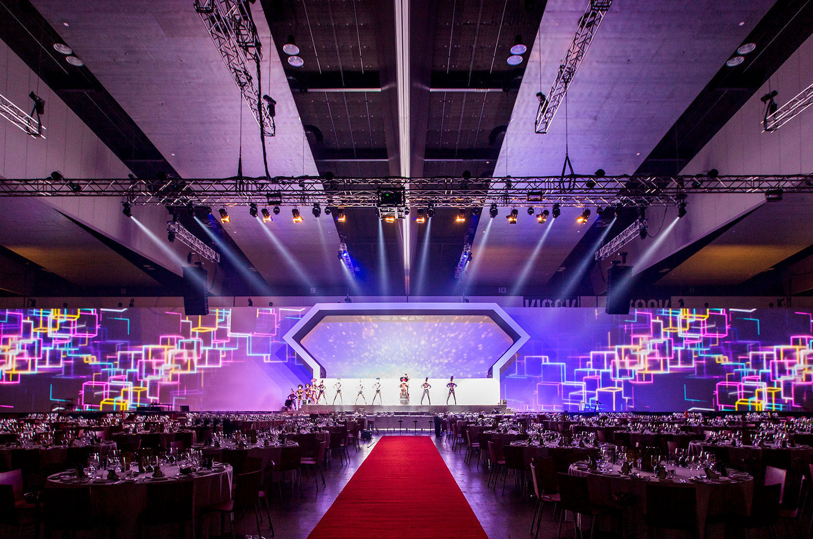 Large indoor event space with a stage and colorful geometric designs on the walls.