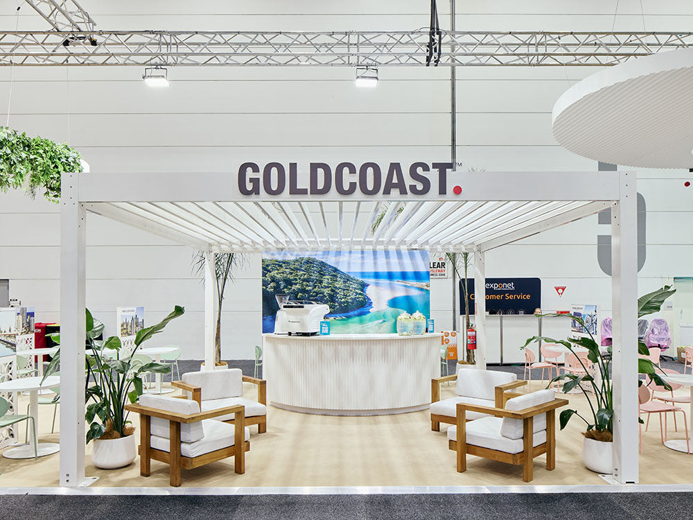 Exhibition stand with 'GOLDCOAST' branding featuring furniture and decor items.
