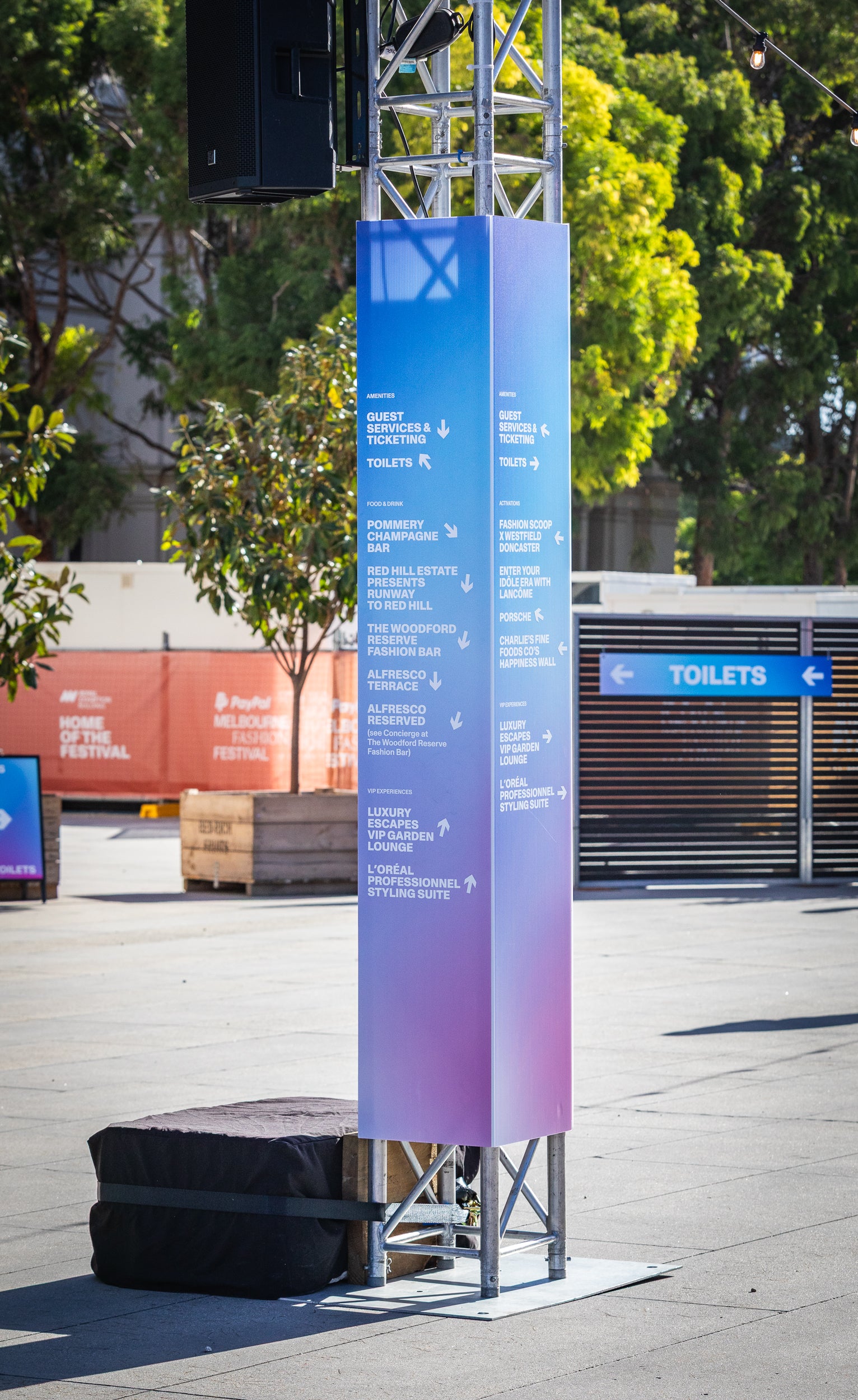 Tall vertical sign with event information on a city street