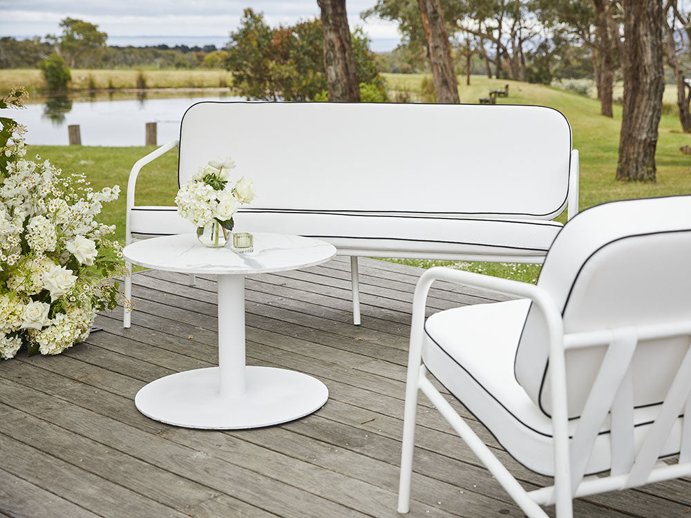 Gigi white outdoor furniture set on a wooden deck with a scenic background