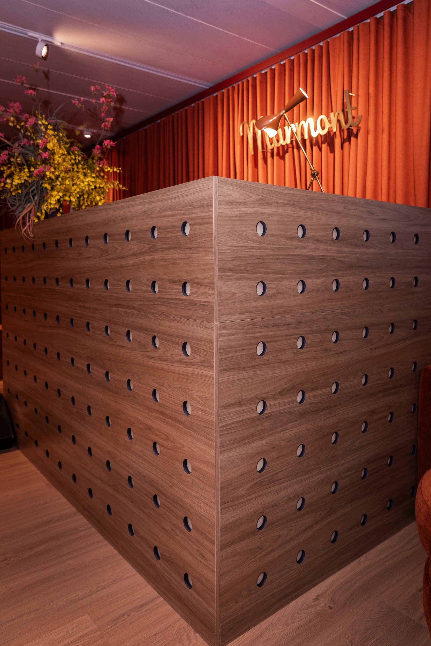 Custom wooden bar with circular cutouts in a room with orange curtains and decorative lights.