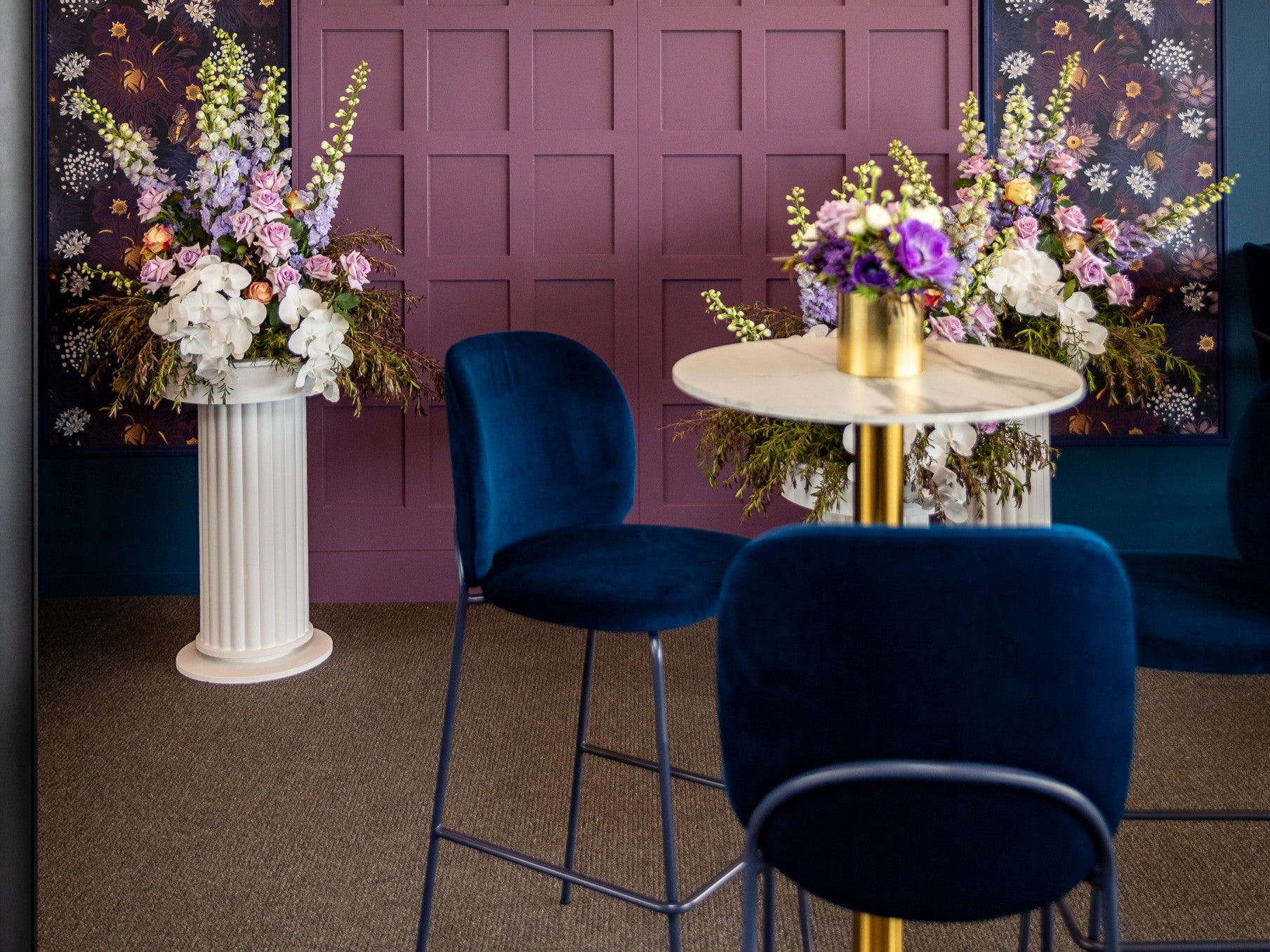 Elegant table setting with navy velvet chairs and white floral centrepiece onsite at a major event