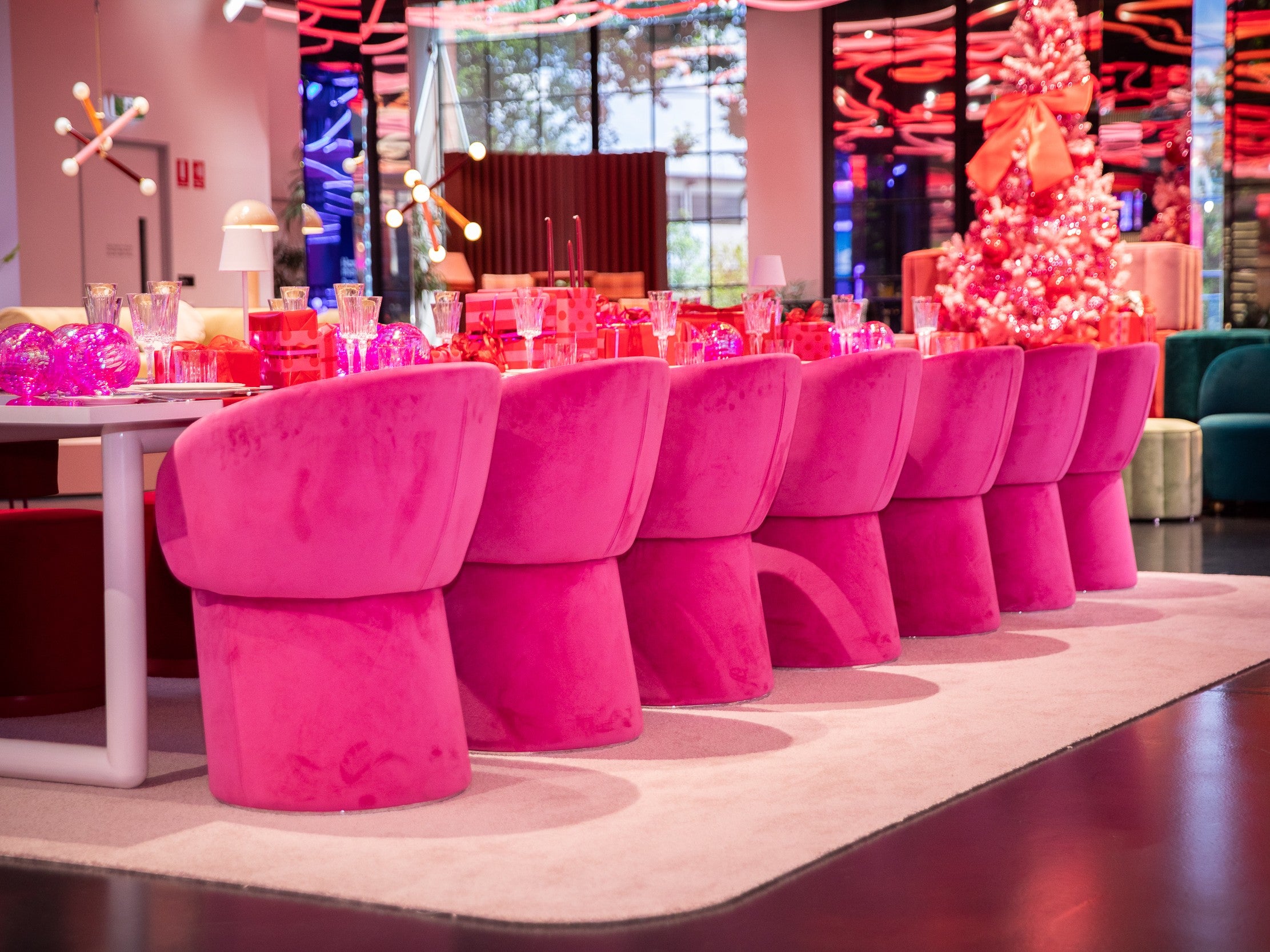 Row of pink chairs at a table with colorful decor.