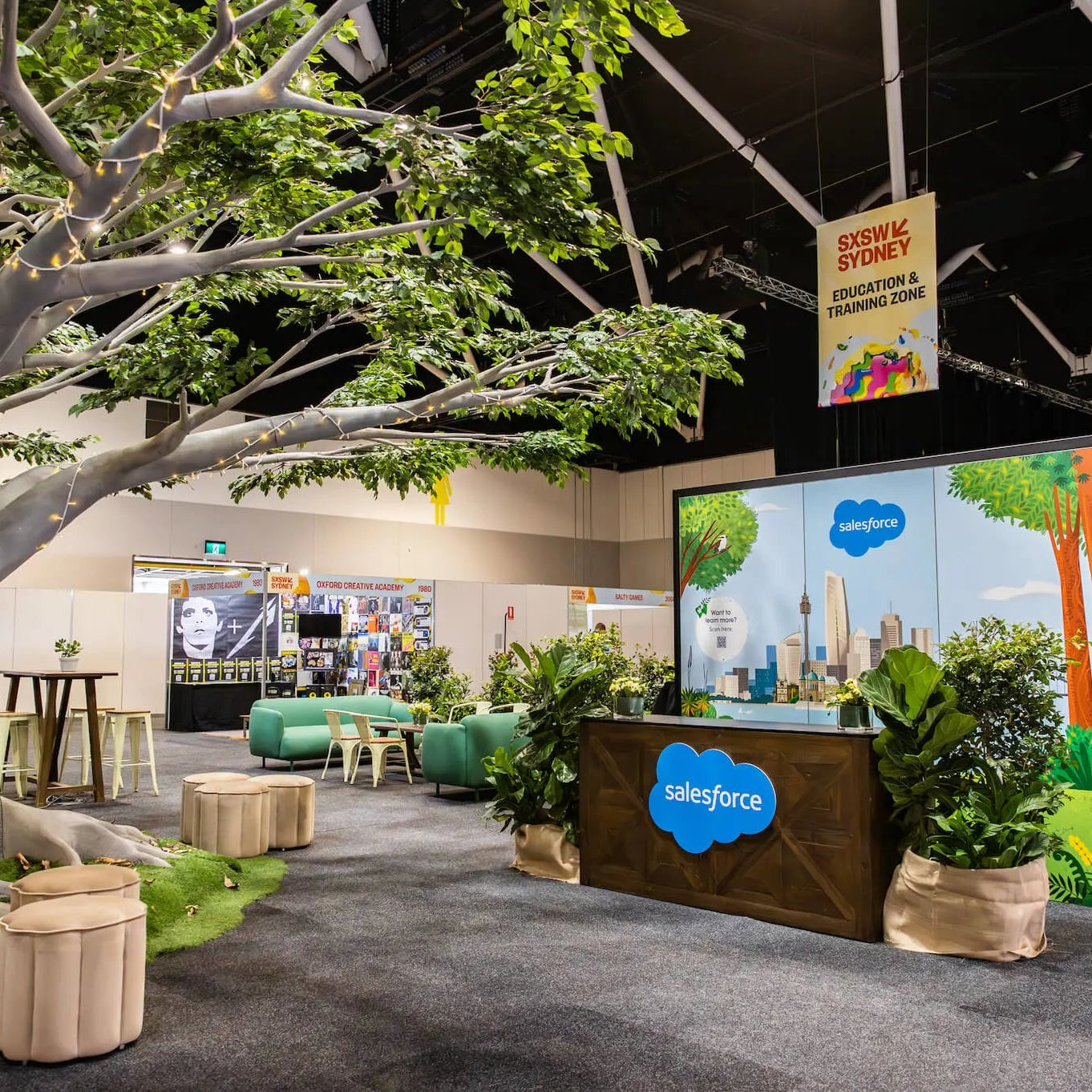 Exhibition area with a large tree, promotional materials, and a Salesforce display.